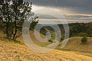 Valley between small hills under dark clouds