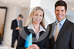 Valued members of a business unit. Portrait of two business professionals standing indoors.