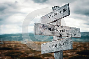 Values, morals and ethics text on wooden sign post outdoors in landscape scenery.