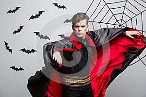 Vampire Halloween Concept - Portrait of handsome caucasian Vampire halloween costume fluttering his red, black cloak.
