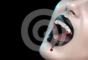 Vampire teeth with dripping blood, Woman`s black bloody lips close-up. Vampire girl fangs. Fashion Halloween art design