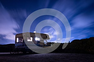Van life concept. long exposure of recreational vehicle, also called camper, parked at night under the stars with clear sky and vi