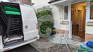 A van packed up with furniture chairs from a home move by the entrance