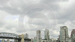 Vancouver BC Canada with Cambie Bridge Condominiums Buildings Moving Clouds and Water Transportation along English Bay Time Lapse