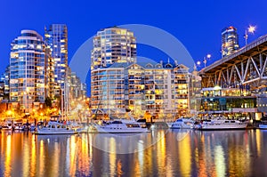 Vancouver BC skyscrapers and Granville Bridge reflection along False Creek at blue hour