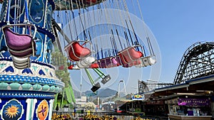 vancouver canada playland The main empty swing that spins with seats without people Rollercoaster in the background