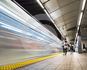 Vancouver City Center station at evening rush hour with trains rushing by and commuters waiting.