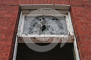 A vandalised broken glass window in a derelict industrial building