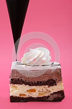 Vanilla and chocolate layered cake with fruit insertions on pink background