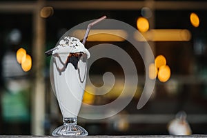 Vanilla chocolate milkshake on a cafe bar with beautiful bokeh of street lamps
