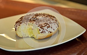 Vanilla cream filled dough nut with white crusting and chocolate sprinkle on top served on white ceramic plate photo