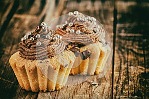 Vanilla cupcake with chocolate topping. Old wooden background.