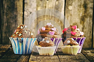 Vanilla cupcake with chocolate topping. Old wooden background.