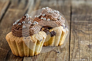 Vanilla cupcake with chocolate topping. Old wooden background.