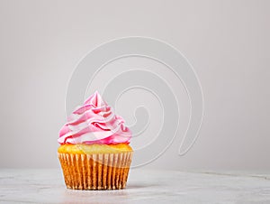 Vanilla Cupcake with pink Buttercream Icing on grey.