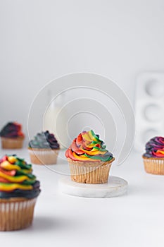 Vanilla cupcake with rainbow frosting surrounded by other multicolored cupcakes