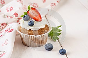 Vanilla cupcake with ripe strawberry and blueberries