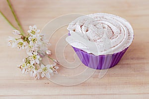 Vanilla cupcake with white frosting and flowers on a table