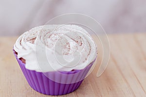 Vanilla cupcake with white frosting and flowers on a table