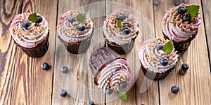 Food banner. Vanilla cupcakes with cream and blueberries on a wooden table