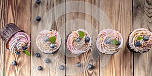 Food banner. Vanilla cupcakes with cream and blueberries on a wooden table