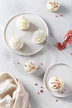 Vanilla cupcakes decorated with white frosting and dried strawberry on gray table. Top view. Cookbook recipe, menu, bakery, pastry