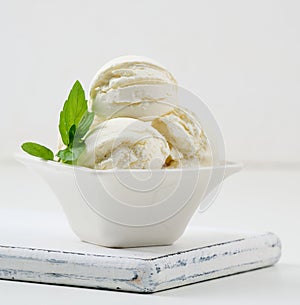 Vanilla ice cream balls with green mint leaf in a white ceramic plate