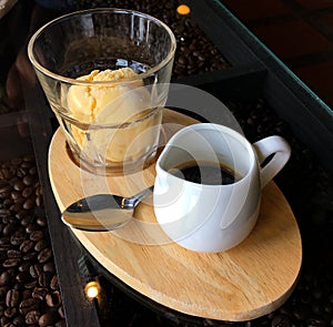 Vanilla ice cream and black coffee in cup on wooden plate
