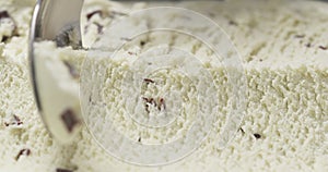 Vanilla ice cream with chocolate chips being scooped close up