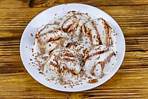 Vanilla ice cream with chocolate topping in white plate on wooden table