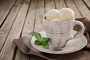 Vanilla ice cream in cup on rustic wooden background