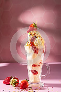 Vanilla ice cream milkshake garnished with fresh strawberry and colourful sprinkles