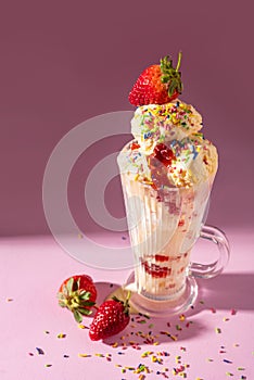 Vanilla ice cream milkshake garnished with fresh strawberry and colourful sprinkles