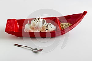 Vanilla ice cream in red gondola shaped plate with diced hazelnuts