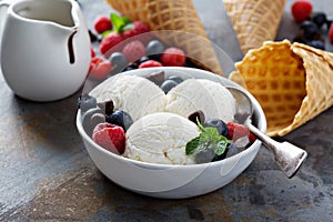 Vanilla ice cream scoops in a bowl with fresh berries