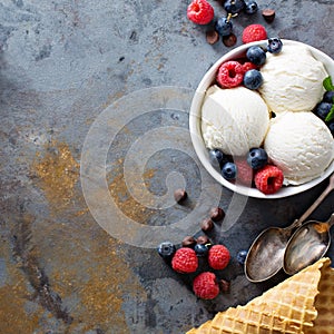 Vanilla ice cream scoops in a bowl with fresh berries