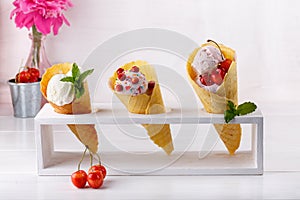 Vanilla ice cream in three waffle cones decorated with various berries