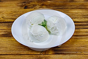 Vanilla ice cream in white plate on wooden table