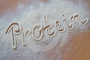 Vanilla protein powder - text `protein` in powder on brown board