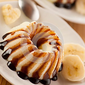 Vanilla pudding with dessert with chocolate syrup and banana sli