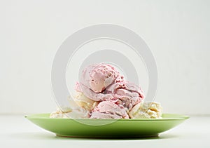 Vanilla and raspberry ice cream scoops on a round green plate