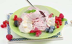 Vanilla and raspberry ice cream scoops on a round green plate