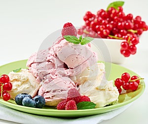 Vanilla and raspberry ice cream scoops on a round green plate