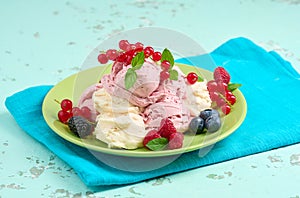 Vanilla and raspberry ice cream scoops on a round green plate