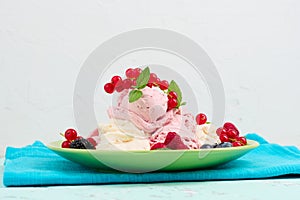 Vanilla and raspberry ice cream scoops on a round green plate