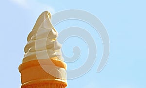 Vanilla Soft Serve Ice Cream Cone Against Sunny Blue Sky with Copy Space