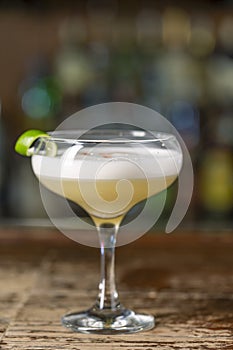 Vanilla Sour cocktail with egg white and lemon juice  on the bar. Blurred background