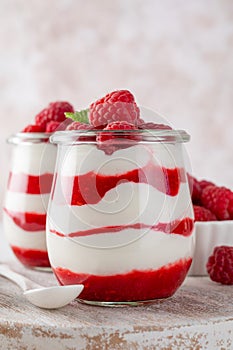 Vanilla white chocolate mousse, trifle, panna cotta or parfait with raspberry sauce in a glass jar. Sweet summer dieting dessert