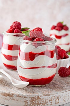 Vanilla white chocolate mousse, trifle, panna cotta or parfait with raspberry sauce in a glass jar. Sweet summer dieting dessert