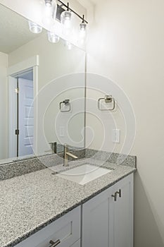 Vanity sink of a bathroom with granite countertop and wall mounted lights